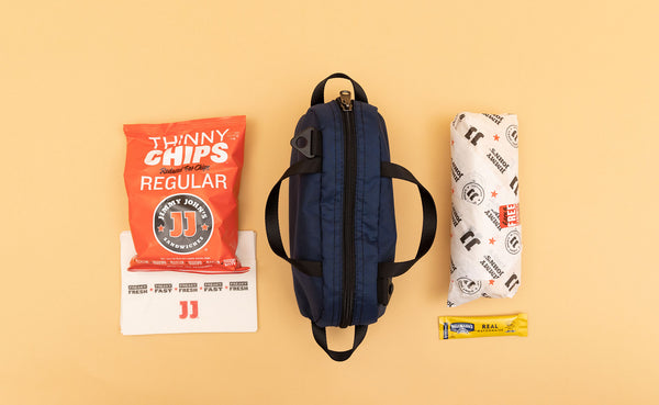 A Navy Parapack Grab Bag with a sub sandwich and chips next to it.